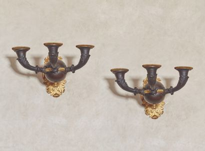 null 
A pair of patinated and gilt bronze sconces, decorated with a sphere holding...