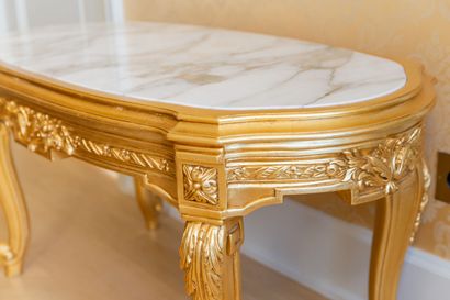 null Table basse en bois sculpté et doré, plateau de marbre blanc encastré. 

Style...