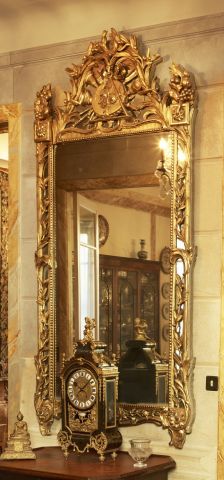 null Grand miroir en bois sculpté et doré à motif de feuillages, attributs de musique...