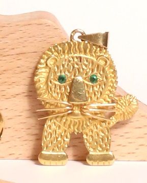  * Pendentif lion stylisé en or jaune 18K 750/000, deux pierres vertes pour les yeux...