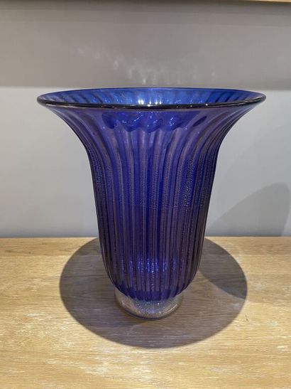 null A large glass vase on a pedestal with a flared neck and blue gadrooned decoration...