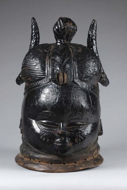 null Sowei helmet mask representing a woman with a hairstyle divided into many buns.
Wood...