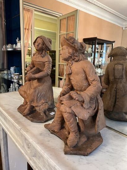 null Two terracotta sculptures depicting a seated young woman cutting a loaf of bread,...
