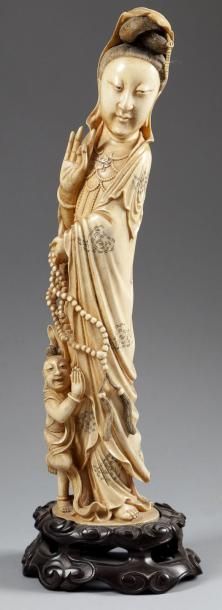 CHINE - XXe siècle Statuette en ivoire à patine jaune, Guanyin debout tenant un rosaire...
