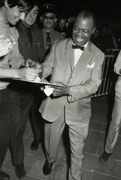 Louis Armstrong signant un autographe, c....