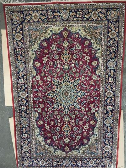 null Keshan. Tapis en laine à fond bordeau entrelacs, fleurs stylisées en écoinçons,...