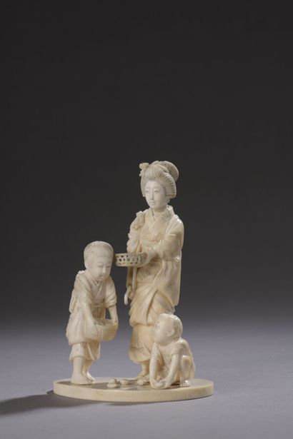 null Okimono en ivoire sculpté, jeune femme debout, accompagnée de deux enfants remplissant...