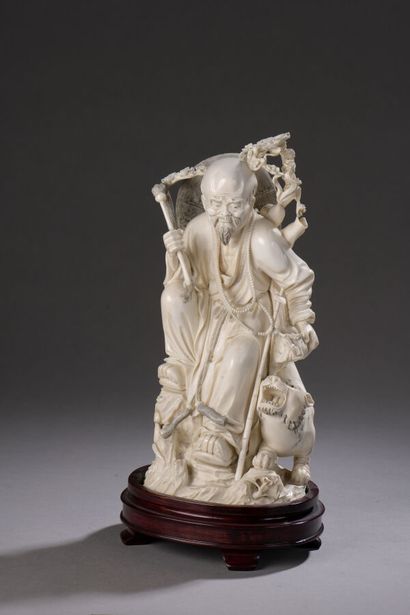null Carved ivory okimono, Luohan standing on a rocky terrace, a flycatcher in his...