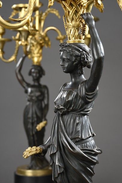 null PAIRE DE CANDELABRES en forme de vestales en bronze patiné tenant une couronne...