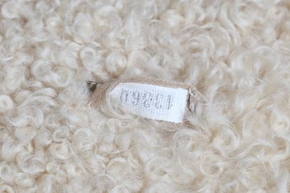 CHANEL Un manteau Chanel couture ivoire en tweed bouclé et doublé d'agneau de Mongolie,...