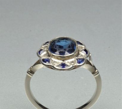 null Bague festonnée en or gris ornée d'un saphir de synthèse ovale entouré de diamants...