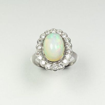 null Platinum ring (850/oo) the scalloped oval top centered with an opal cabochon...