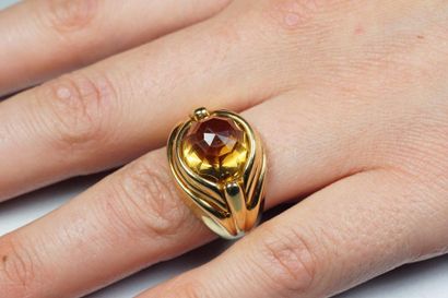 null 18K (750/oo) yellow gold ring centered on a faceted citrine cabochon in an openwork...