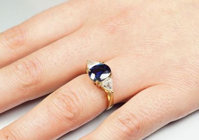 null 18K (750/oo) yellow gold ring centered on an oval sapphire calibrating approximately...