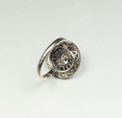 null Platinum ring (850/oo), the round plate centered with a white imitation stone...
