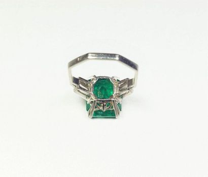null Platinum ring (850/oo), centered on a rectangular cut-faceted emerald calibrating...