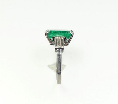 null Platinum ring (850/oo), centered on a rectangular cut-faceted emerald calibrating...