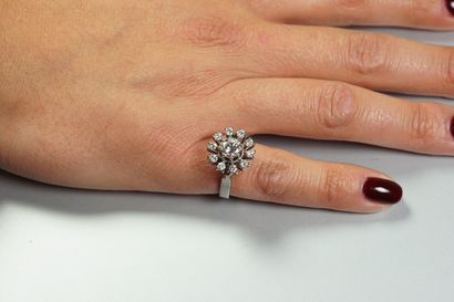 null Bague "Fleur" en or gris 18K (750/oo) centrée d'un diamant taille brillant calibrant...