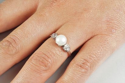 null Platinum ring (850/oo) centered on a cultured pearl supported by two patterns...