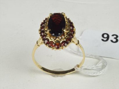 null Bague en or jaune 18K (750/oo) ornée d'un grenat ovale entouré d'un motif ciselé...