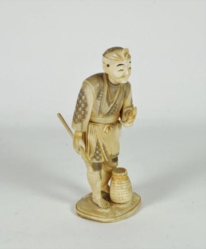 null Okimono en ivoire sculpté et réhaussé à l’encre représentant un pécheur debout...