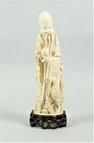 null CHINE Statuette en ivoire représentant un sage debout tenant une pêche de longévité,...