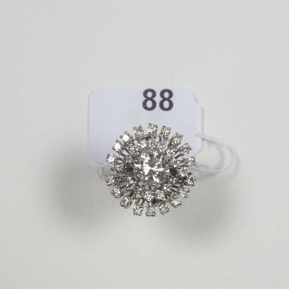 null Bague "Fleur" en or gris 18K (750/oo) ornée d'un diamant taille brillant calibrant...