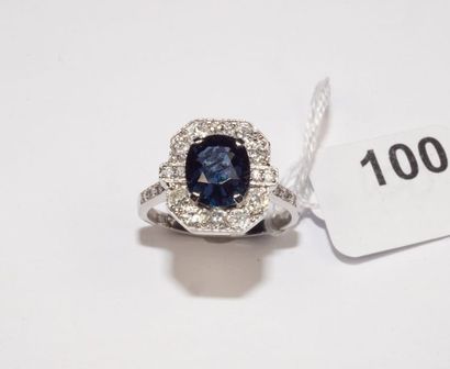 null Bague en or gris 18K (750/oo) centrée d'une pierre bleue ovale, l'entourage...