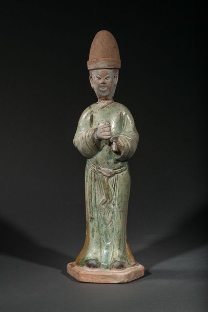 null Standing dignitary dressed in a long tunic and wearing a cap. Partially glazed...