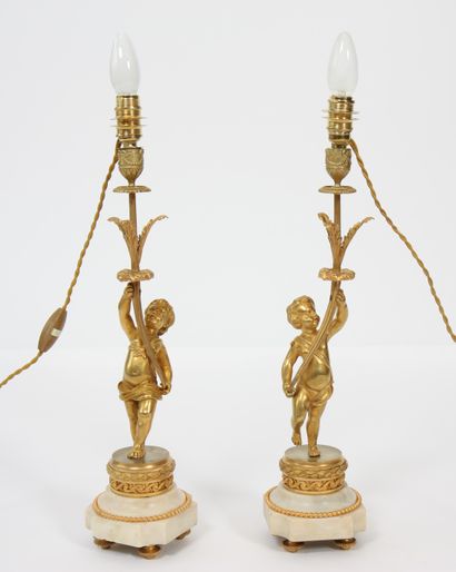 null PAIR OF GILT BRONZE "PUTTO" LAMPS
With one arm of light supported by a putto...