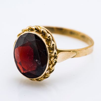 null 18 karat (750 thousandths) yellow gold ring set with an oval garnet in a twisted...
