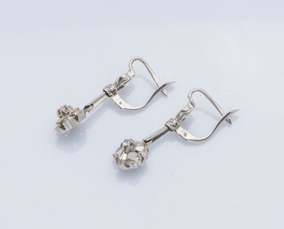 null A pair of 18K (750 ‰) white gold earrings holding a flower pendant set with...