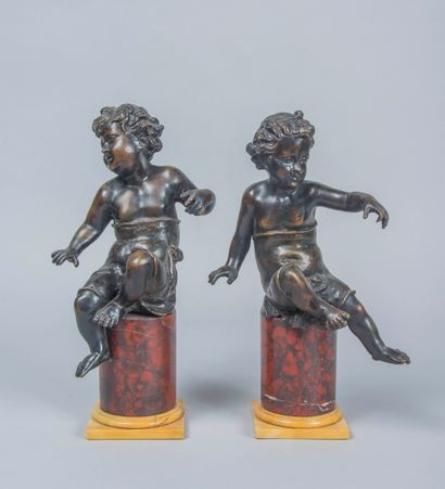 null Pair of bronze subjects with brown patina representing putti resting on a red...
