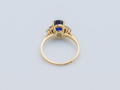  An 18K (750 ‰) yellow gold ring set with an oval synthetic sapphire shouldered with...