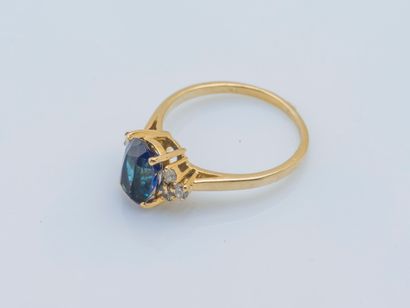  An 18K (750 ‰) yellow gold ring set with an oval synthetic sapphire shouldered with...