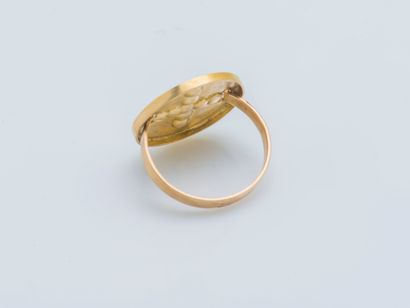  An 18K (750 ‰) yellow gold ring the round bezel adorned with a lily cross highlighted...