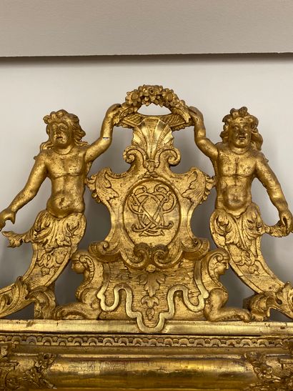 null 
Miroir en bois doré à large fronton orné de deux figures masculines retenant...