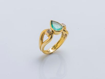 null 18K (750 ‰) yellow gold ring set with a pear-cut emerald shouldered by two brilliant-cut...