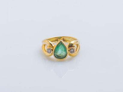 null 18K (750 ‰) yellow gold ring set with a pear-cut emerald shouldered by two brilliant-cut...