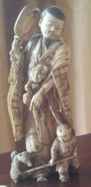 null  OKIMONO en ivoire sculpté d'un personnage à l'éventail, un enfant à ses pieds.
Japon,...