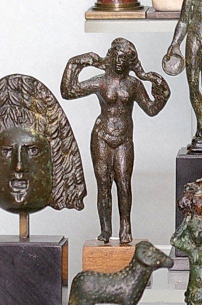 null Vénus en bronze représentée debout nue, les bras levés enroulant ses cheveux....