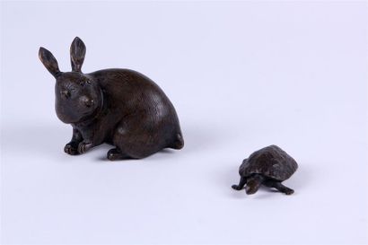 null OKIMONO en bronze patiné représentant un lapin assis, une patte levée. Le pelage...