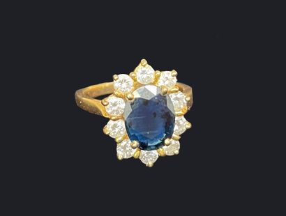 null *Bague en or jaune 750 millièmes sertie d'un saphir ovale dans un entourage...