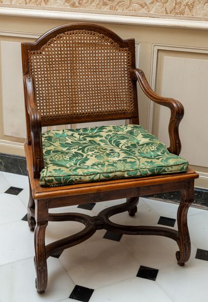 null A moulded walnut caned armchair with a low cut-out back. The base has interior...
