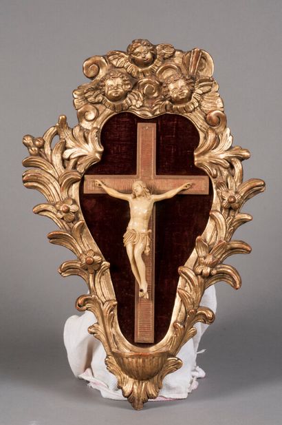 null **Crucifix en ivoire dans un important cadre mouvementé ormant bénitier en bois...
