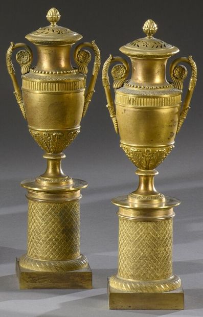 null A pair of ormolu cassolette urns with pierced lids, the pedestal applied with...
