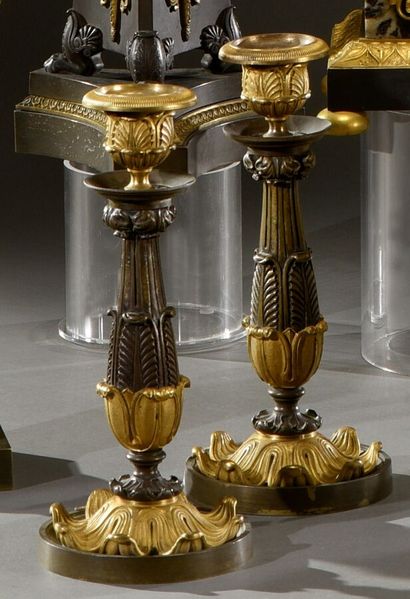 null A pair of ormolu and patinated candlesticks, the fluted shaft with acanthus...
