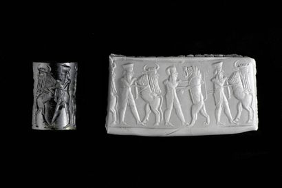 null Cylinder seal engraved with a mythological battle scene. Two heroes wearing...