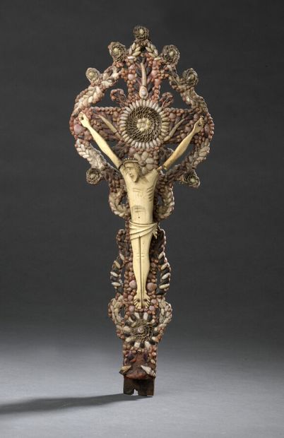 null Crucifix en os sculpté sur fond de micro coquillages et micro cailloux.

Art...