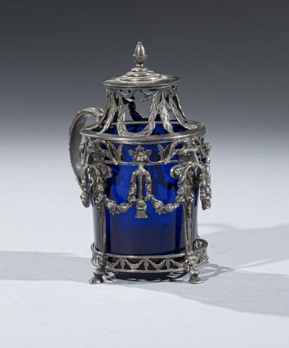 null A covered mustard pot in cast and chased silver, resting on four uprights with...